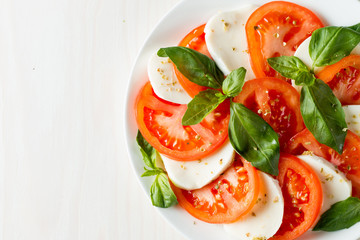 Close-up photo of caprese salad with ripe tomatoes, basil, buffalo mozzarella cheese. Italian and Mediterranean food concept. Fresh and healthy organic meal. Starter and antipasti. 