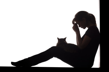 silhouette of a woman sitting on the floor on a white isolated background with a cat in her arms, a...