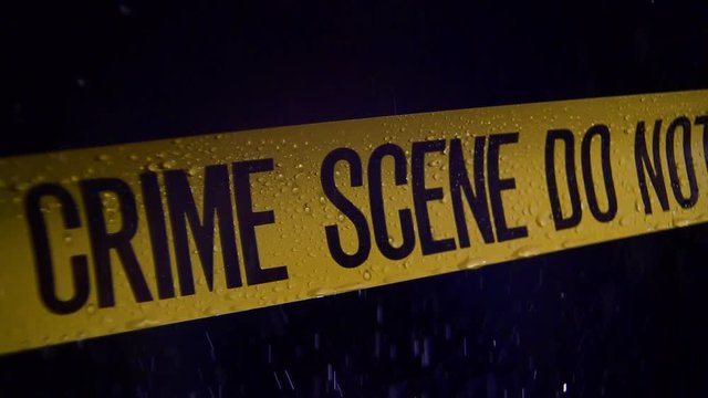 CRIME SCENE TAPE, ISOLATED, ON A RAINY NIGHT.  SLOW MOTION CLOSE UP.