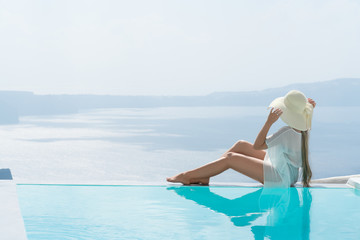 young woman enjoying a magnificent view of Santorini near the pool.