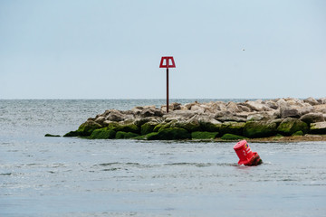 red buoy in floating water in front of a rocky promontory