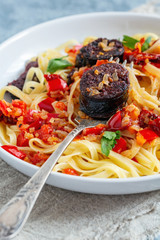 Italian pasta with tomato sauce and blood sausages.