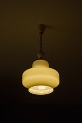 The light of the retro chandelier (white glass) suspended on chains to the ceiling at night....