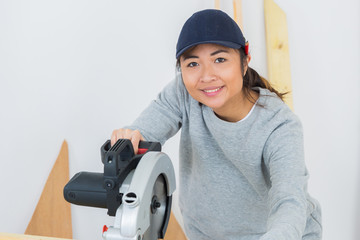 young woman posing while cutting the wood