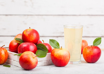 Glass of fresh organic apple juice with healthy red apples in box on wooden background