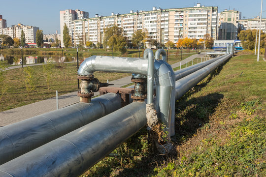 Modern Elevated Heat Pipes. Pipeline above ground, conducting heat to heat city. Urban heat line in metal insulation in residential quarter of city. Open laying on pillars. Municipal heat supply