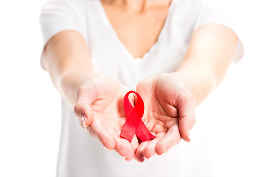 cropped image of woman showing red ribbon in hands isolated on white, world aids day concept