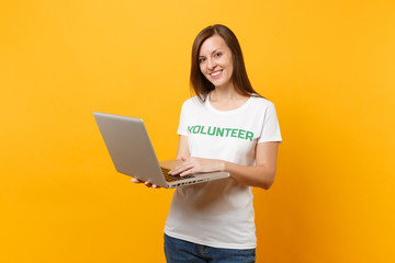 Portrait of woman in white t-shirt with written inscription green title volunteer using laptop pc...