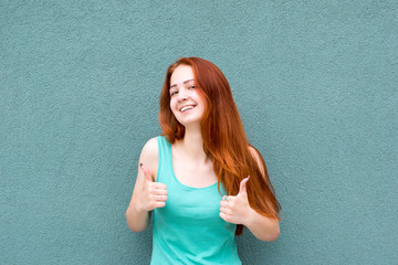 Happy smiling red-haired woman showing thumbs up