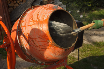 Concrete mixer on the construction site. The builder pours sand into a concrete mixer. Cement...