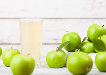 Glass of fresh organic apple juice with healthy green apples in box on wooden background