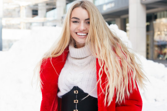 winter, fashion, people concept - fashion Portrait of a beautiful young woman walks around the city smiling red fur coat close-up snowflakes cold winter, breathe fresh air at frost winter day. sunset