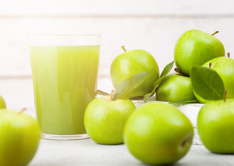 Glass of fresh organic apple juice with healthy green apples in box on wooden background