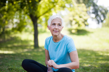 Naklejka na ściany i meble Portrait of smiling senior woman relaxing after exercising