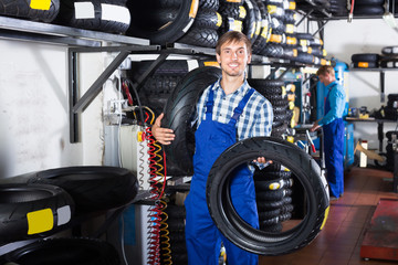 Obraz na płótnie Canvas Happy working man standing with new tires