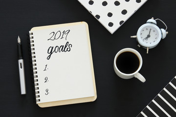 Naklejka premium Top view 2019 goals list with notebook, cup of coffee over wooden desk.