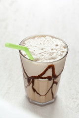 White Frappe Coffee Glass with iced drink on a light wooden table.