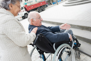 an old woman is pushing husband in wheelchair