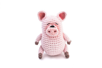 Knitted pink pig on a white background.