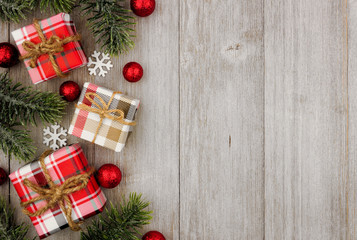 Christmas side border of red and white patterned gifts and tree branches on a light gray wood...