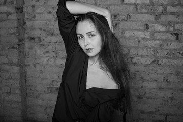 Black and white portrait of a young woman on a brick background. 