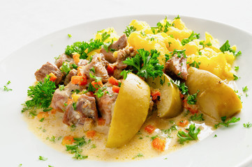chops of turkey stewed with white wine and sour cream, apples and vegetables  garnished with potato and decorated with parsley