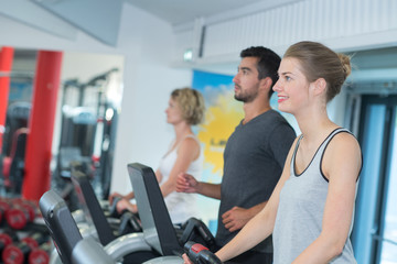 Fototapeta na wymiar People using exercise machines in gym