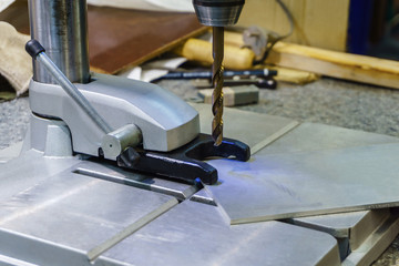 small drill press ready for work on a blurred workshop background
