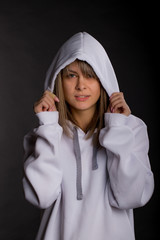 Beautiful young woman in a large white hooded sweatshirt. Studio portrait on black background