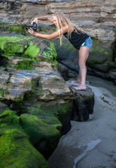 blond girl with camera on seashore