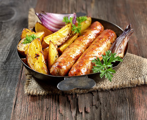 grilled, juicy sausages in a pan on a wooden background.rustic style.