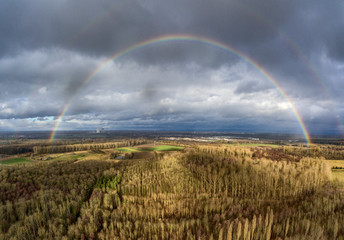Obraz premium rainbow over field with blue sky and clouds