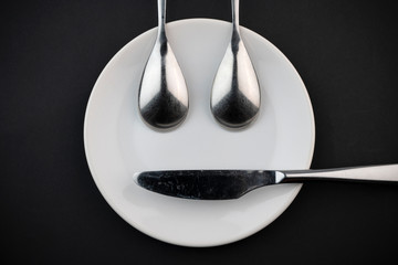 Figuur van een bordje van twee lepels en een mes.