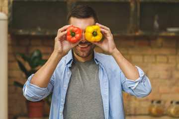 Funny chef puts peppers on the front of every eye cover eyes with it smiling in loft kitchen.