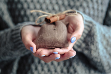 Obraz premium Gorgeous manicure, pastel tender color nail polish, closeup photo. Female hands hold a simple gifts over knit grey background