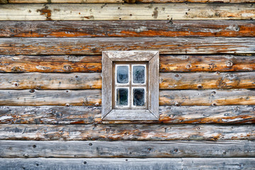 Facade of an old log house with a small window