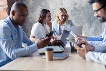 Full concentration at work. Group of young business people working and communicating while sitting at the office desk together with colleagues sitting in the background.