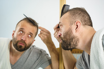 Obraz premium Man using comb in bathroom