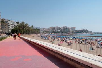 Obraz premium Paseo de la playa de Poniente de Benidorm en España con gente irreconocible paseando, tomando el sol en la arena y bañandose en el agua