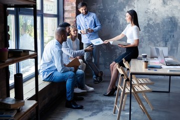 Full length of young modern people in smart casual wear having a meeting in the creative office