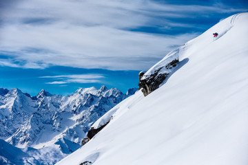 Skier skiing down a snowy steep mountain