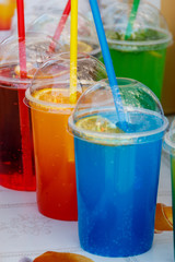 Colorful cold toning cocktails in plastic cups with cocktail straws