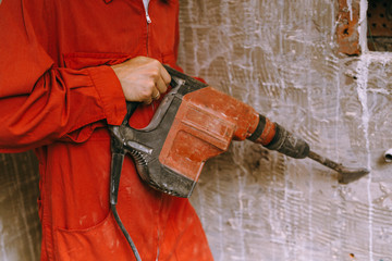 Repairman using drill machine to remove tiles