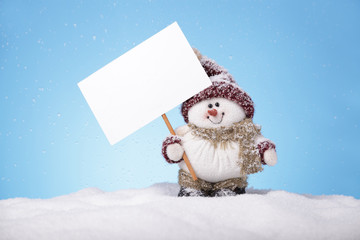 Snowman on snow holding a blank card