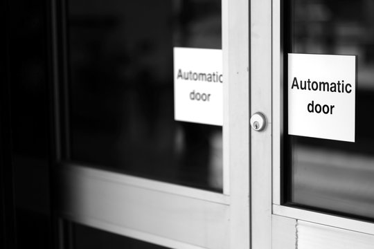 Doors of glass and metal with a lock and signs with the words "automatic doors".