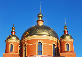 Fototapeta na wymiar Russian Orthodox Church on the background of blue sunny sky. Orthodox church golden domes and crosses. Church of the New Martyrs and Confessors of Belgorod. Belgorod, Russia 2018