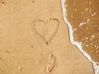 Fototapeta na wymiar Heart written on sandy beach with wave near sea. Happy valentine's day concept. Summer vacation and honeymoon for newlyweds. Hello summer. Space for text. Happy holidays