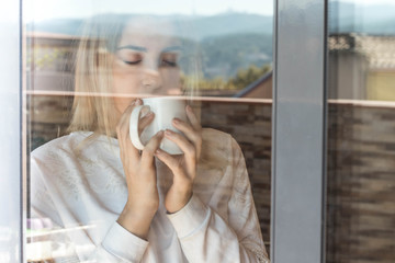 Girl looking through a window with coffee