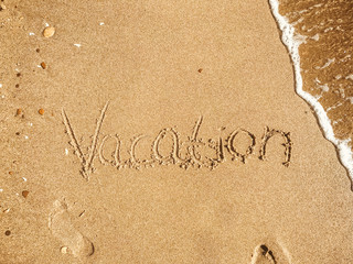 Vacation text written on sandy beach with wave near sea. Summer vacation concept. Hello summer. Travel and wanderlust. Space for text. Happy holidays. Time to relax