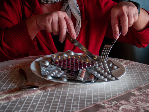 Concept of medicine and health care. A person cutting several tablets of pills on his plate